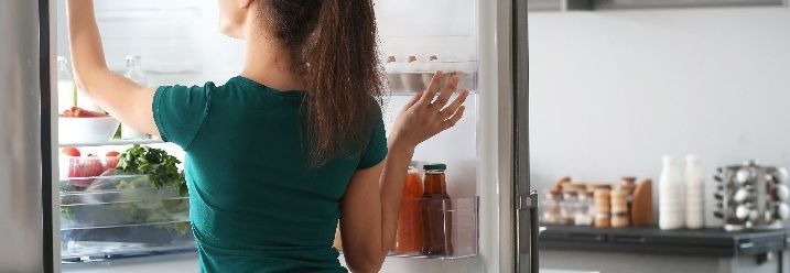 Frau an offenem Kühlschrank